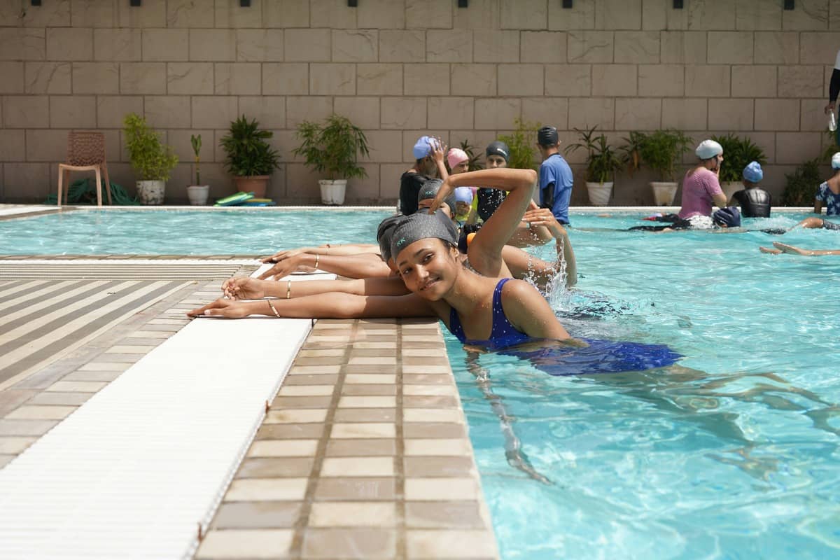 A swimming teacher talking with a parent at the poolside before an Everyone Swims lesson in Cheltenham