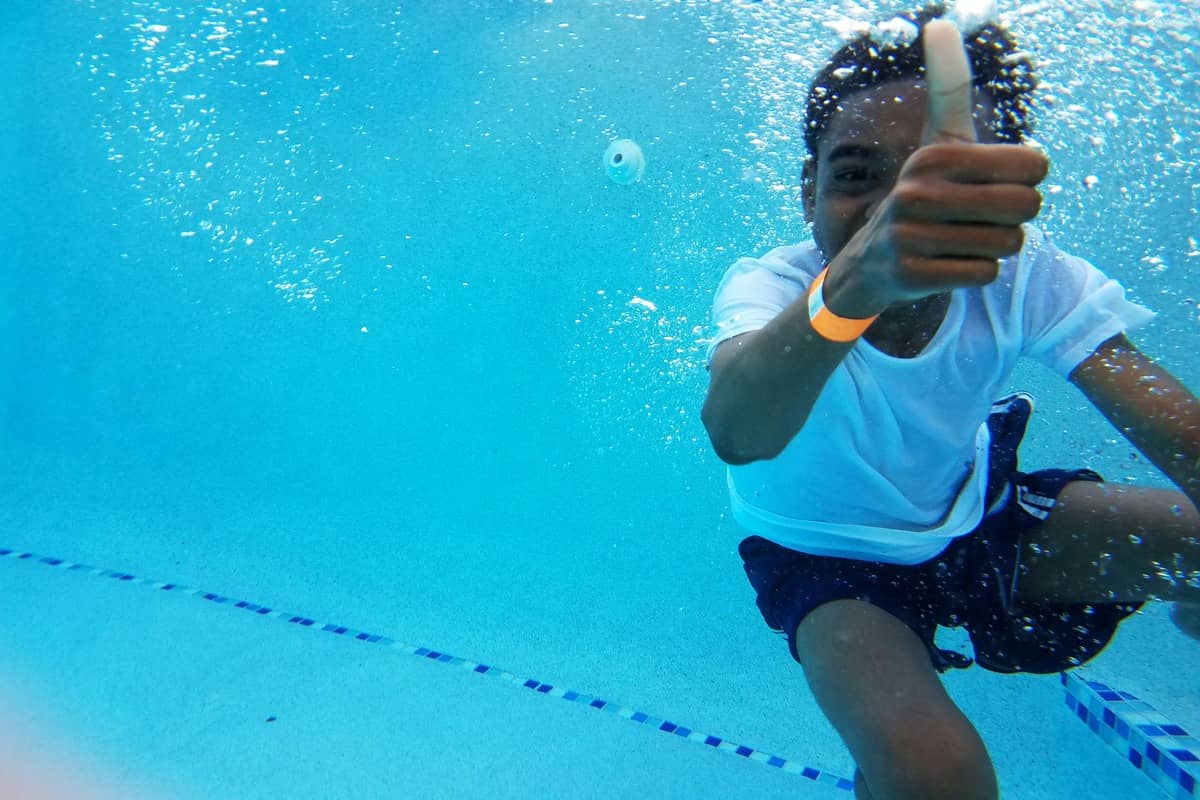 Adults and children taking a swimming lesson together in a pool at an Everyone Swims class in Cheltenham